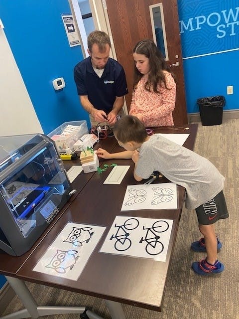 Thomas Brambley leading two young students through a maker activity.