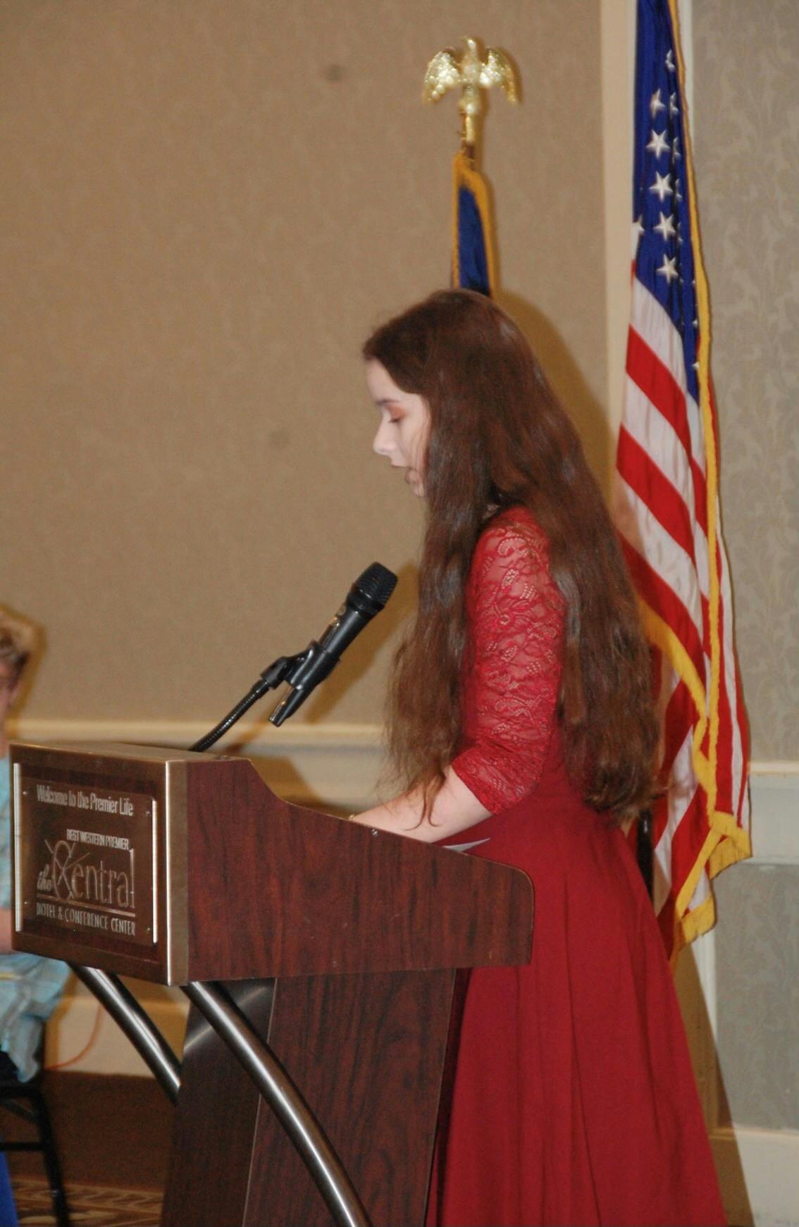 Middle school student speaks at lectern for an honor society induction.